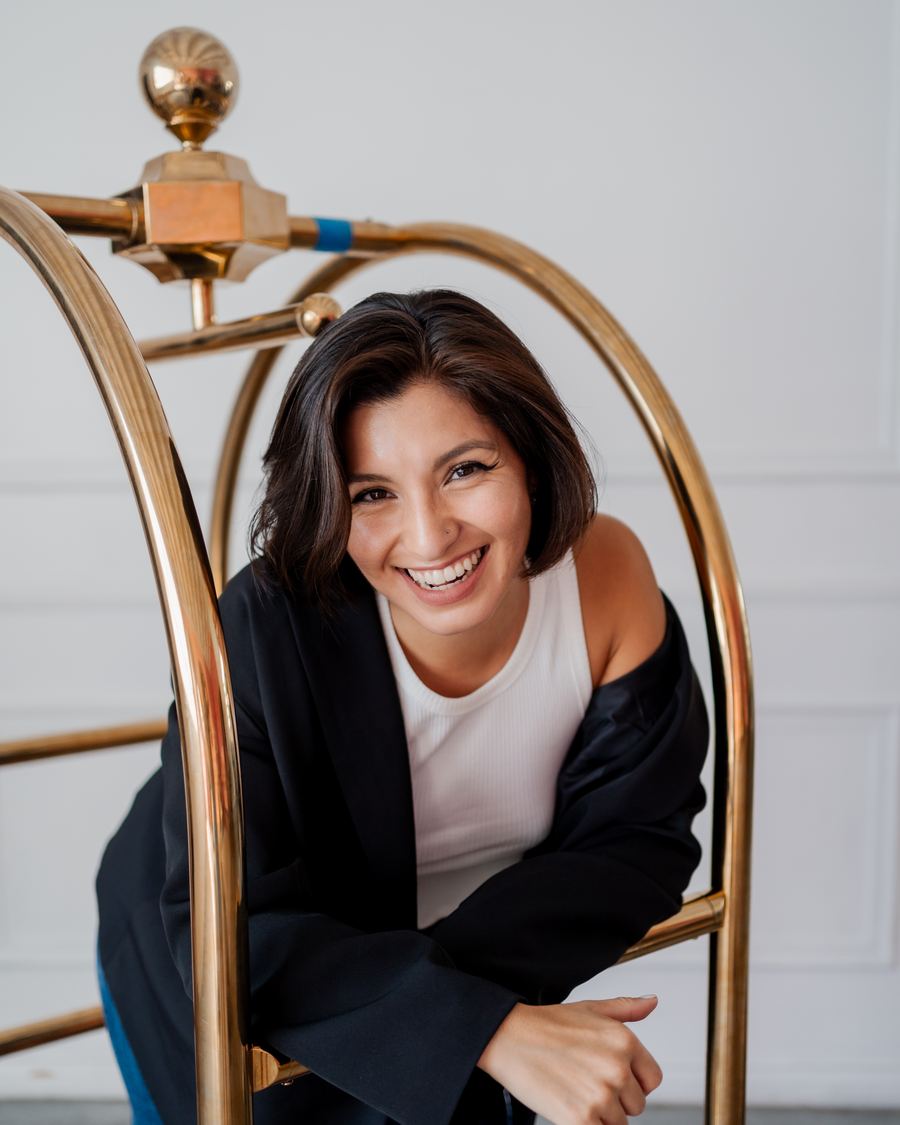 Valerie Rosas leaning on a brass hotel luggage cart
