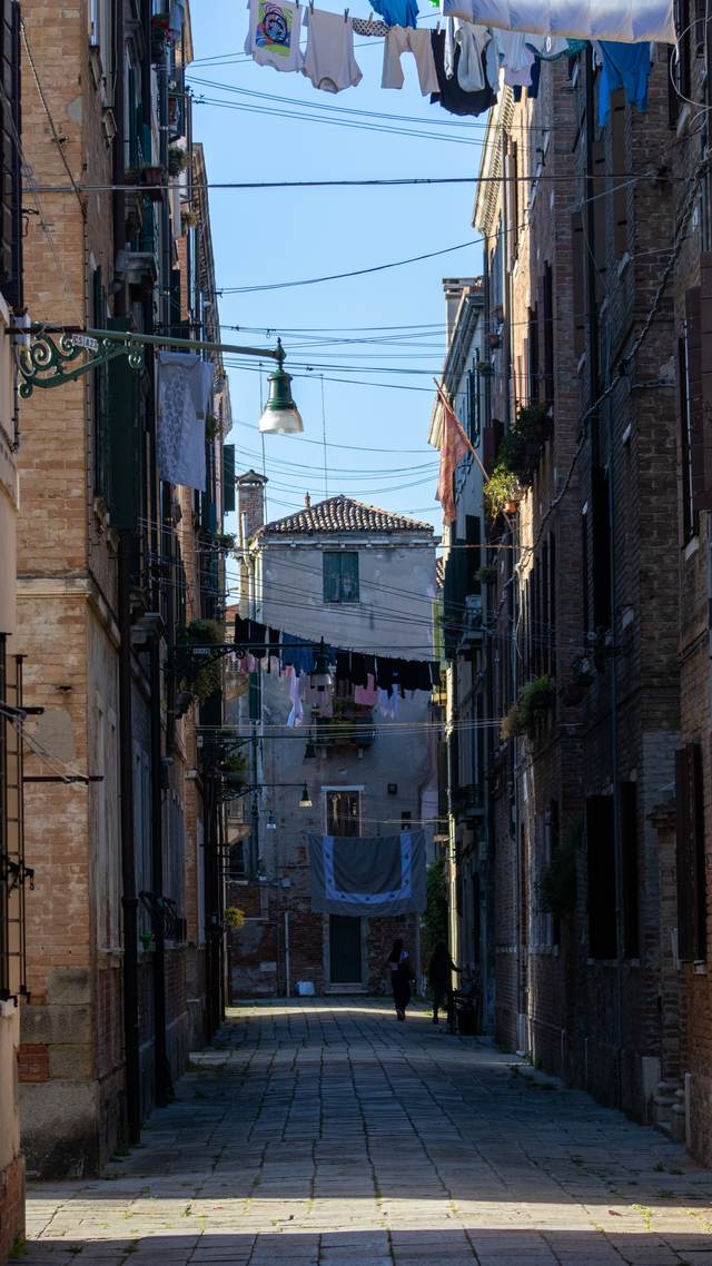 Empty Venetian street lit by hanging lamps at dawn